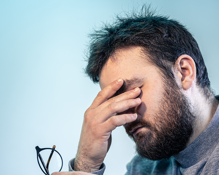 Tired man rubbing eyes due to stress